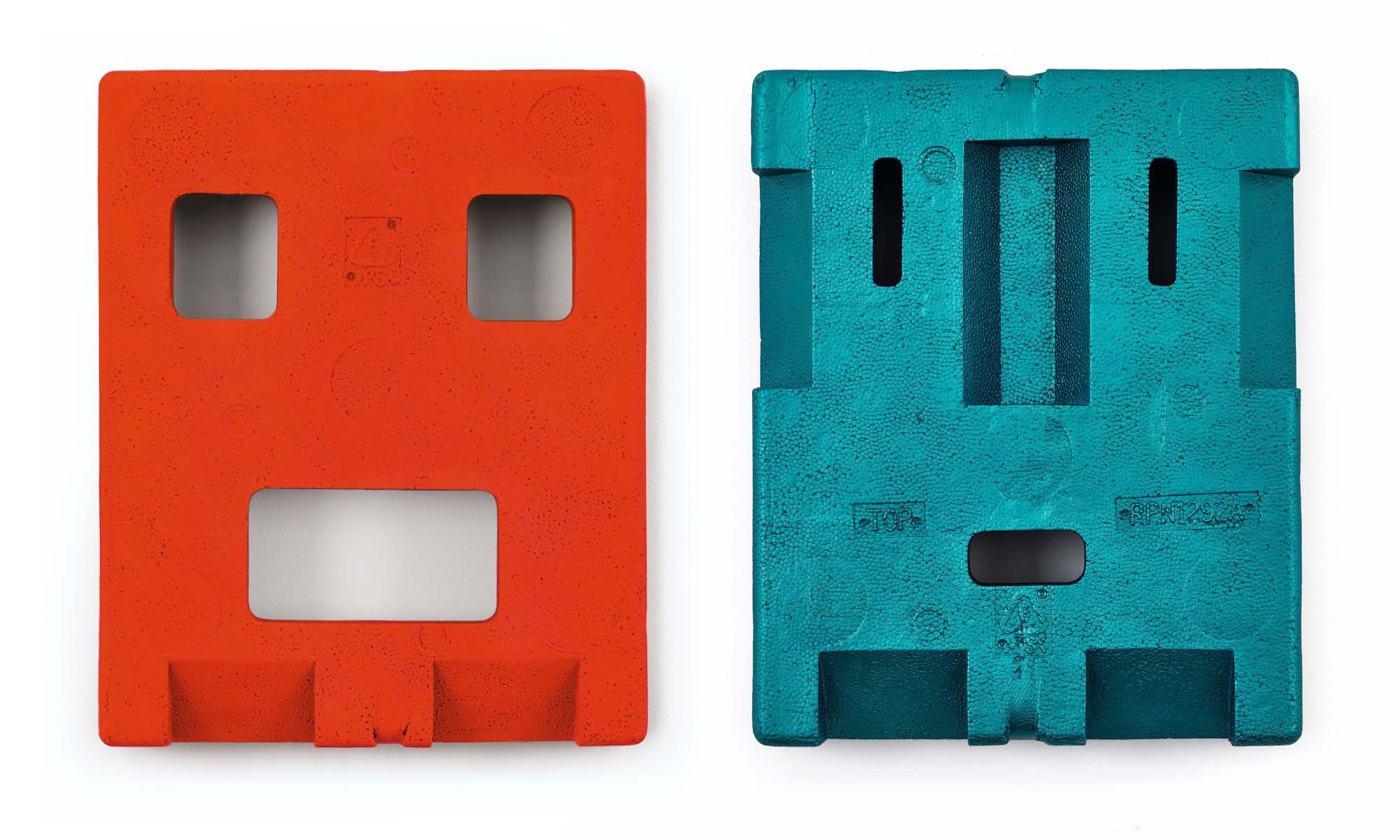 Two bronze casts of polystyrene packaging that resemble faces or masks. One is painted a bright orangey-red, the other a metallic turquoise. 