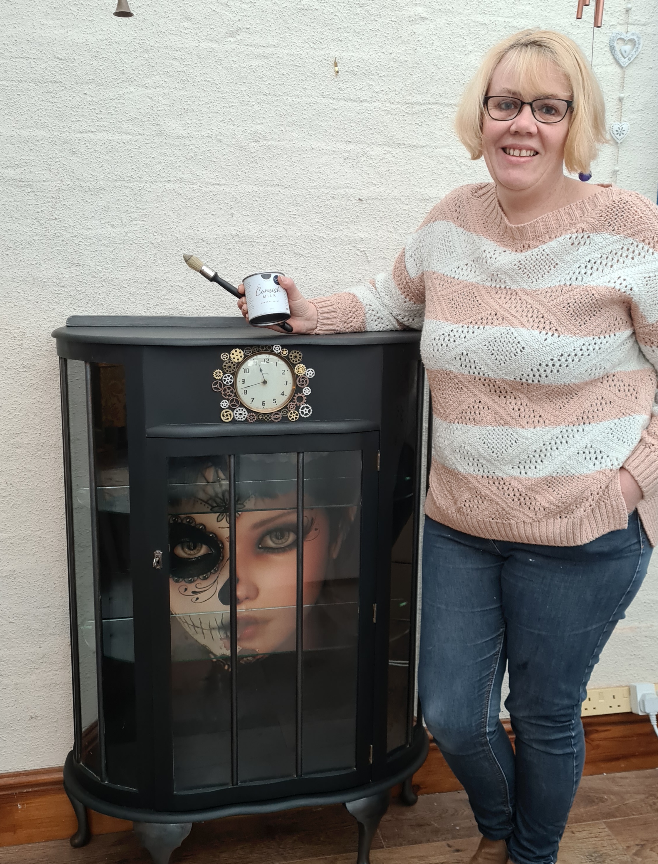 A photo of me standing with an upcycled cocktail cabinet painted by me in a Steampunk theme  